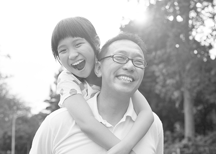 Father and daughter smiling outdoors because they have insurance