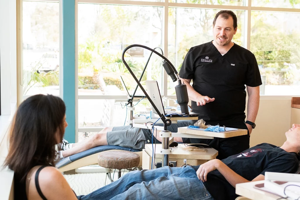 Orthodontist explaining Invisalign for Teens to a mother and teenage patient during consultation