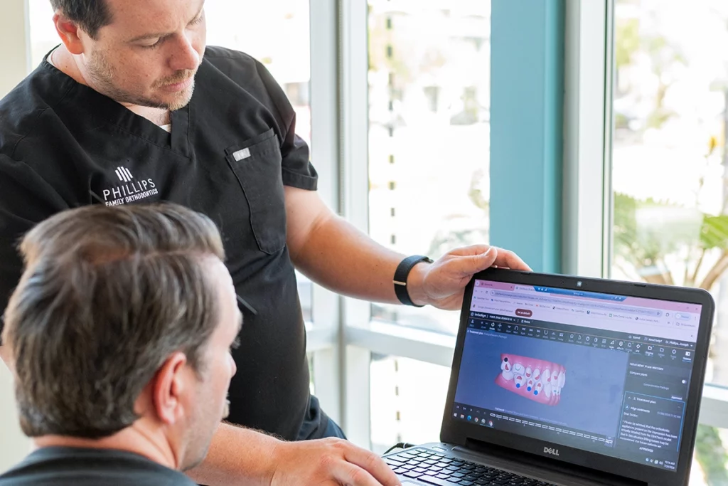 Orthodontist showing an adult patient Invisalign software, teeth scans, and treatment plan for clear aligners