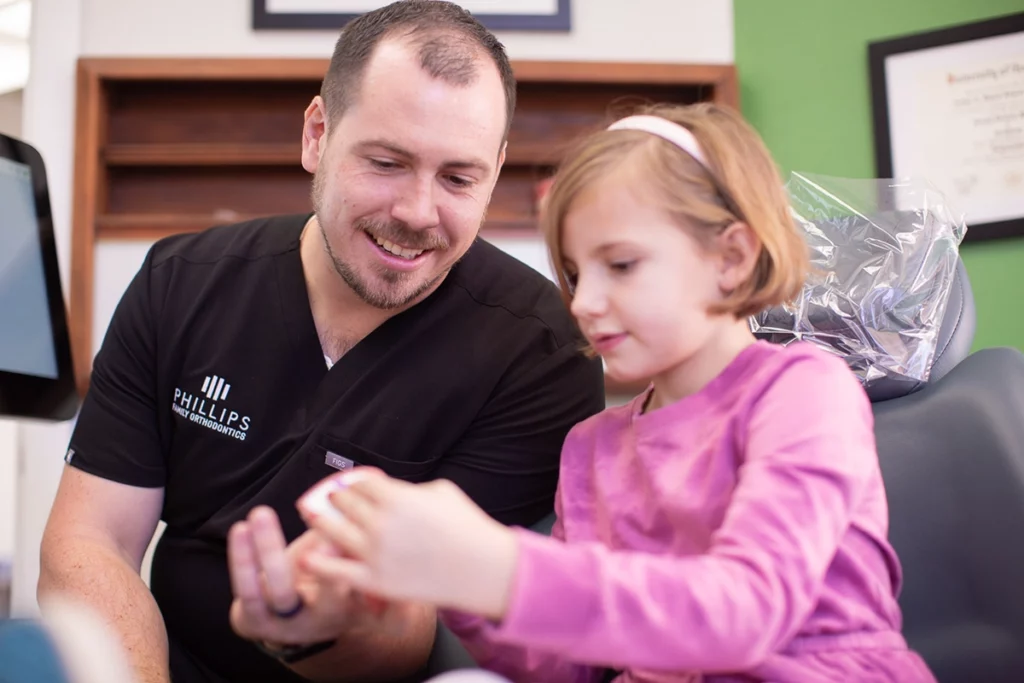 Dr. Phillips laughing with a child patient while discussing braces for kids treatment options at Phillips Family Orthodontics.